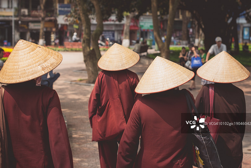 越南河内街头，身着传统服饰、头戴锥形帽子的妇女图片素材