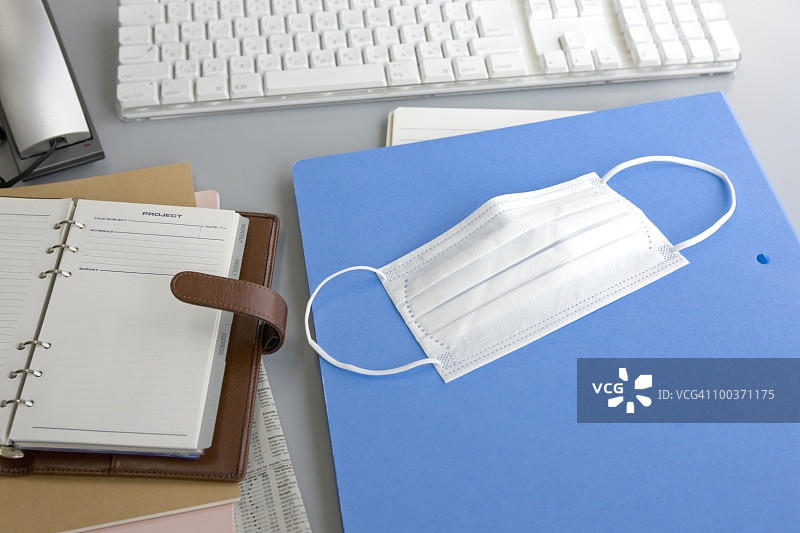 笔记本，文件，日记和外科口罩放在办公桌上图片素材