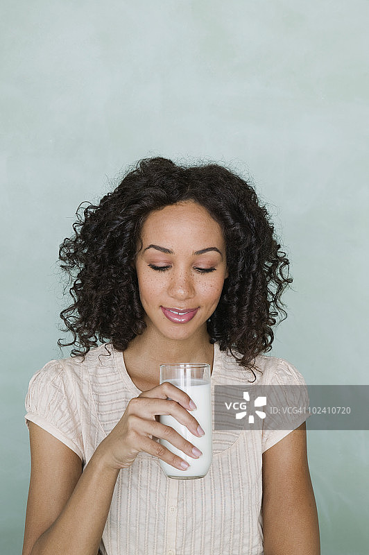 年轻女子拿着一杯牛奶，特写图片素材