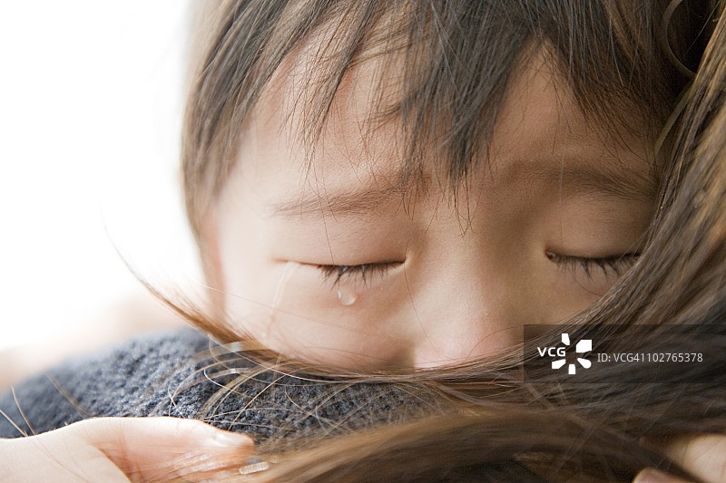 一个学龄前的女孩在妈妈的怀里哭泣图片素材