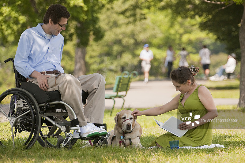一对夫妇带着服务型狗在波士顿的公园里读书图片素材