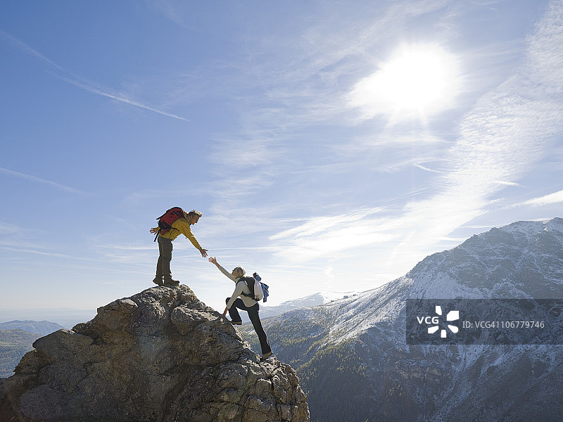 登山者在山脊上向队友伸出援助之手图片素材
