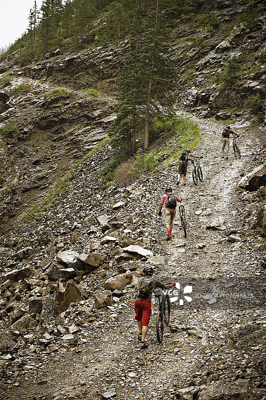 美国，科罗拉多州，峰丘，山地自行车手推着自行车上山图片素材
