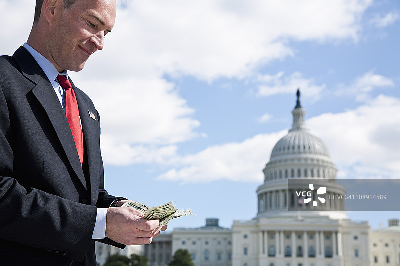 一位政客在美国国会大厦前数钱图片素材