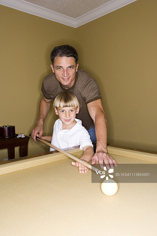 父亲在教他年幼的儿子如何打台球图片素材