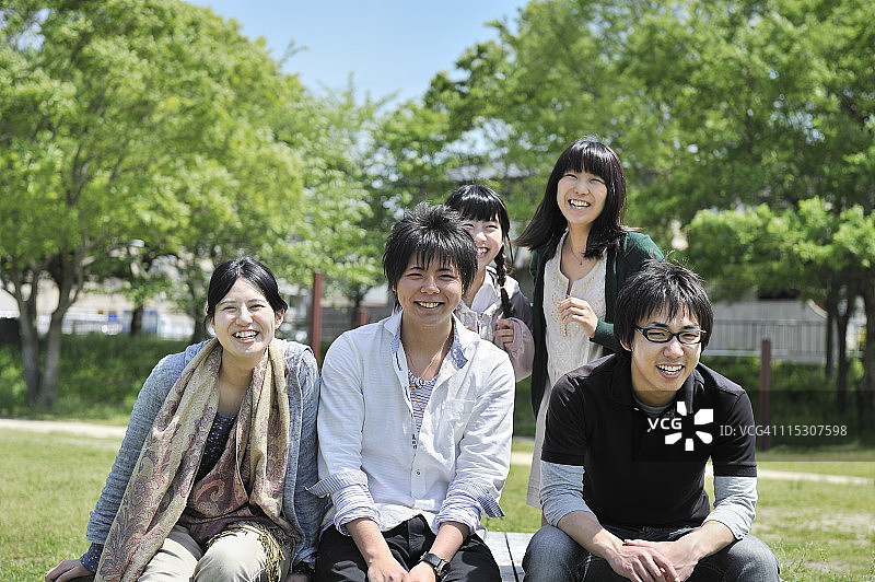 五个年轻人坐在长椅上，微笑着图片素材