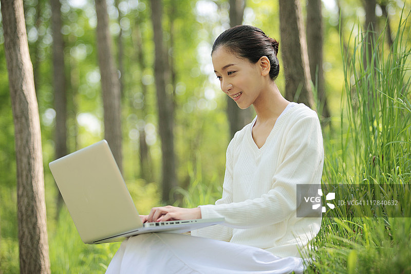 年轻女子在大自然中使用电脑图片素材