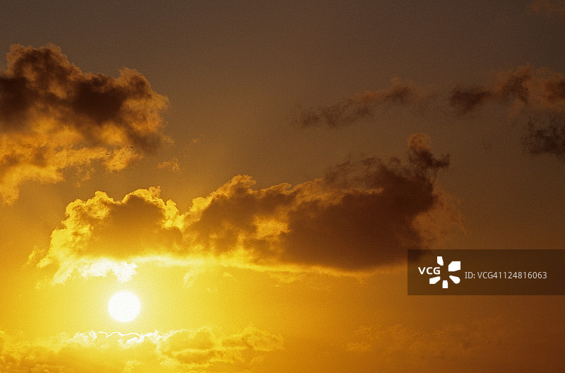 夏威夷，太阳球在云中在戏剧性的黄色日落天空图片素材