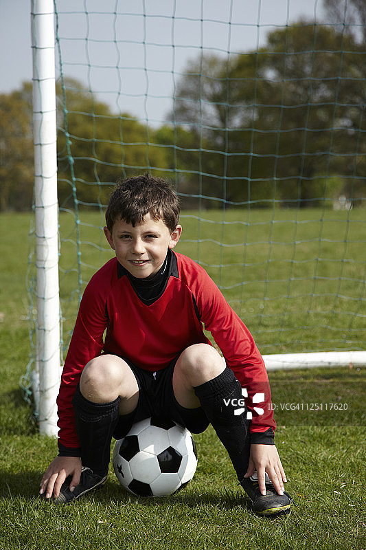 一个男孩坐在足球上图片素材