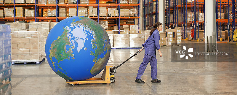 女工在仓库里用手推车拉着一个大蓝球图片素材