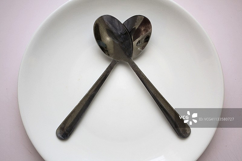 两个勺子放在白色盘子里。图片素材