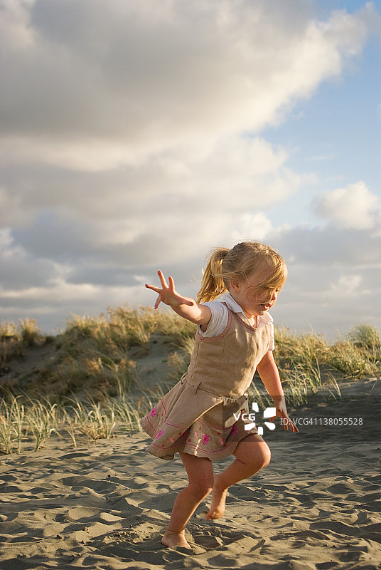 女孩在沙滩上玩沙丘图片素材