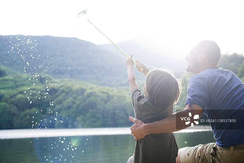 父子钓鱼，男孩用渔网捕鱼图片素材