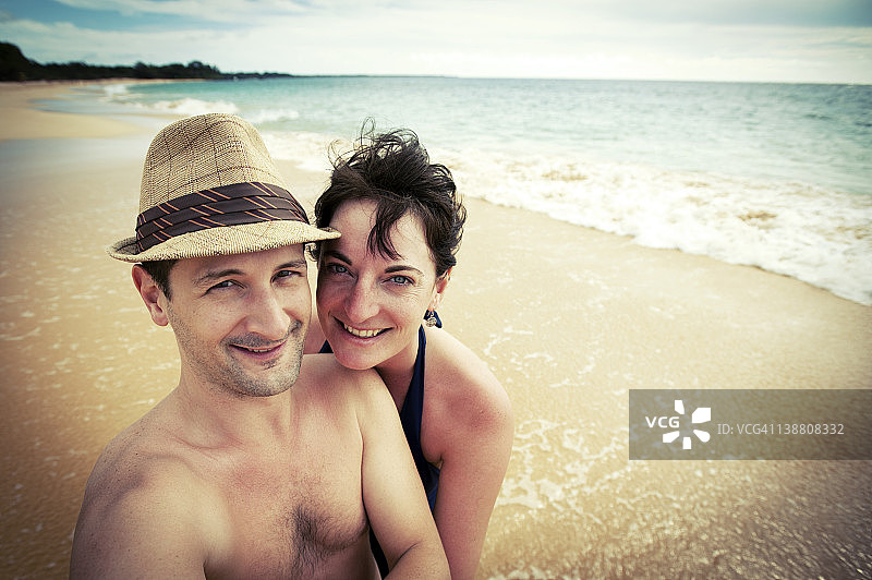 一对情侣在以海洋为背景的海滩上摆姿势图片素材