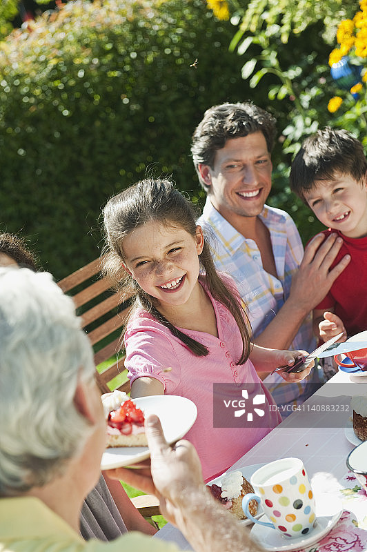 德国，巴伐利亚，一家人微笑着在花园里享用咖啡和蛋糕图片素材