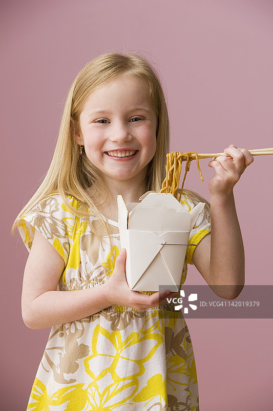 微笑的女孩吃着纸盒里的亚洲食物图片素材