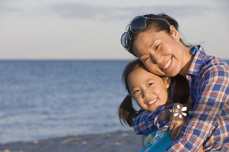母亲在海滩上拥抱女儿图片素材