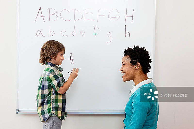 老师和男孩在白板上写字母图片素材