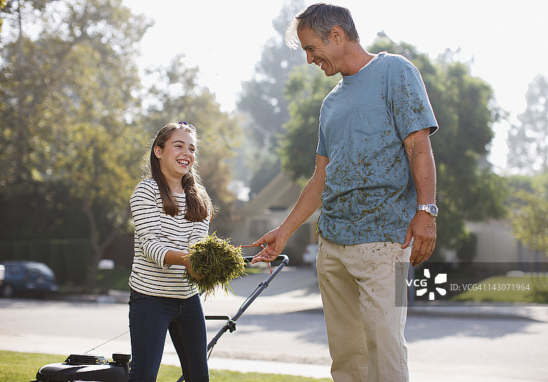 父亲和女儿一起修剪草坪图片素材