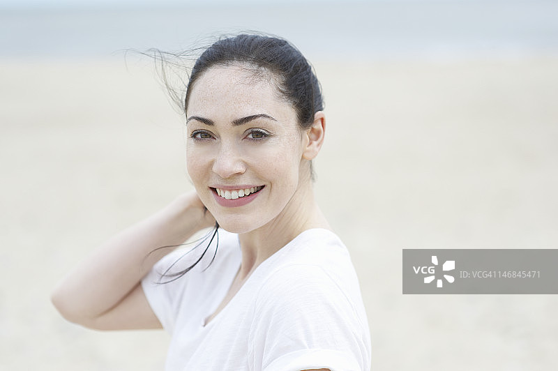 在海滩上，头发随风飘动的女人。图片素材