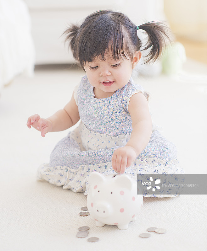 美国，新泽西州，泽西城，女婴的肖像(12-17个月)玩存钱罐图片素材