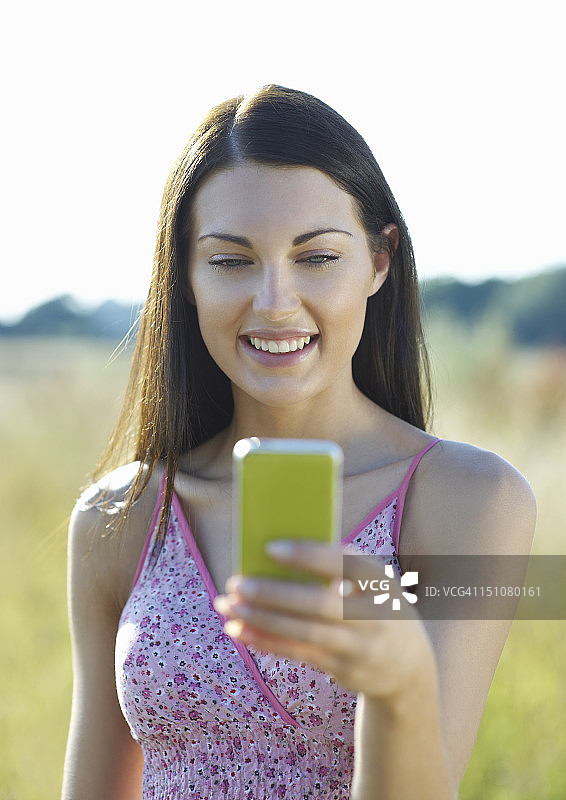 女人一边用手机一边笑。图片素材