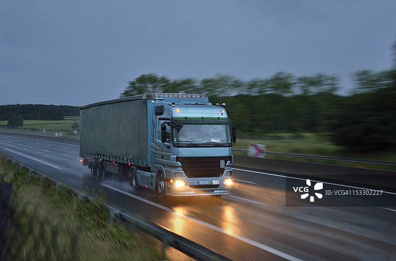 黄昏时分，重型货车行驶在潮湿的高速公路上图片素材