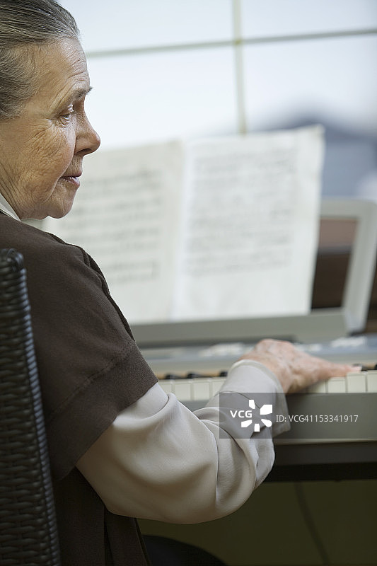 一位年长的女士坐在钢琴前图片素材