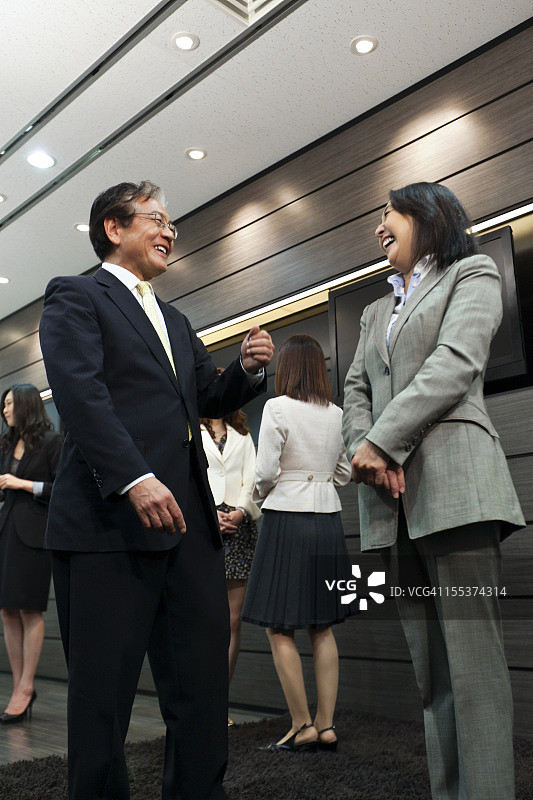 快乐成熟的日本商人与他的女同事交谈。图片素材