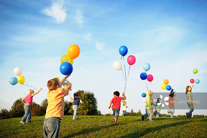 一群孩子拿着气球在阳光下奔跑图片素材