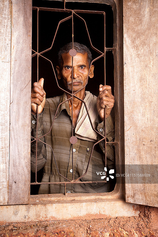 一位沉思的印度农村老人从窗户往外看图片素材