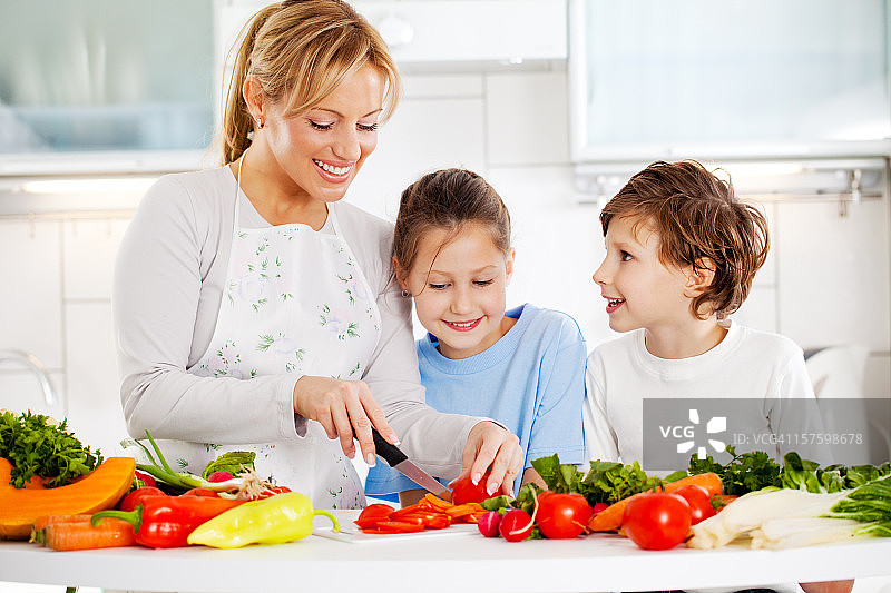 母亲和孩子们在厨房切菜。图片素材