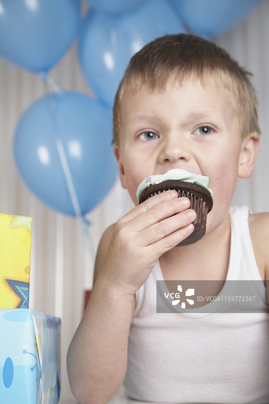 小男孩在吃纸杯蛋糕。图片素材