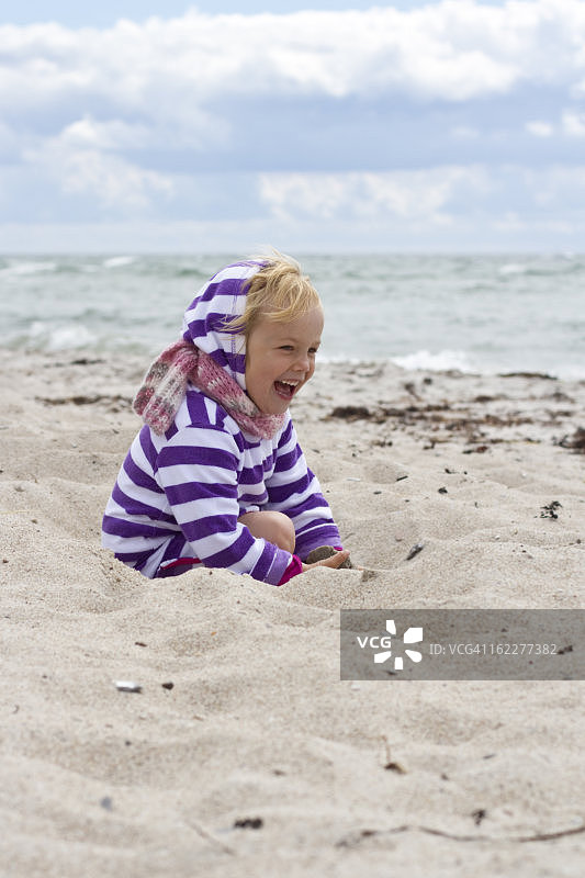 快乐的女孩在沙滩上玩沙子图片素材
