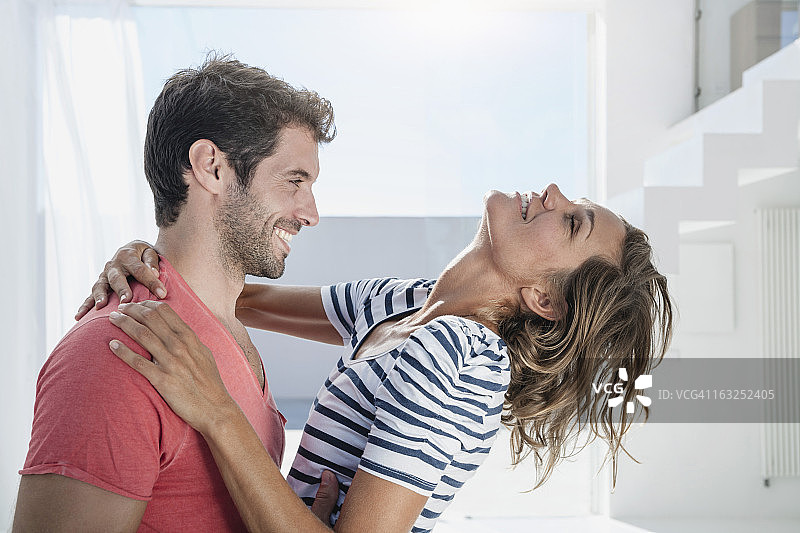 西班牙，一对中年夫妇在现代公寓里拥抱彼此图片素材