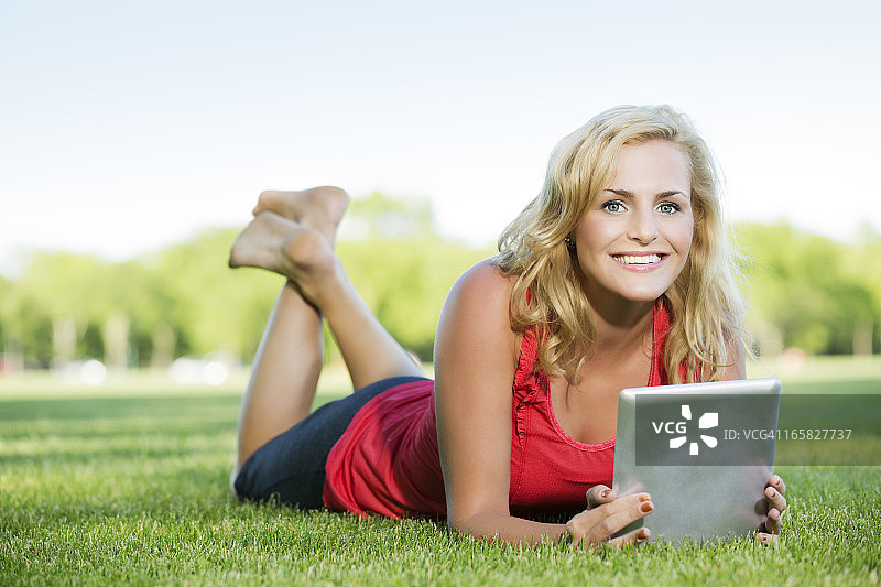 一个年轻女子在公园里用平板电脑看书图片素材