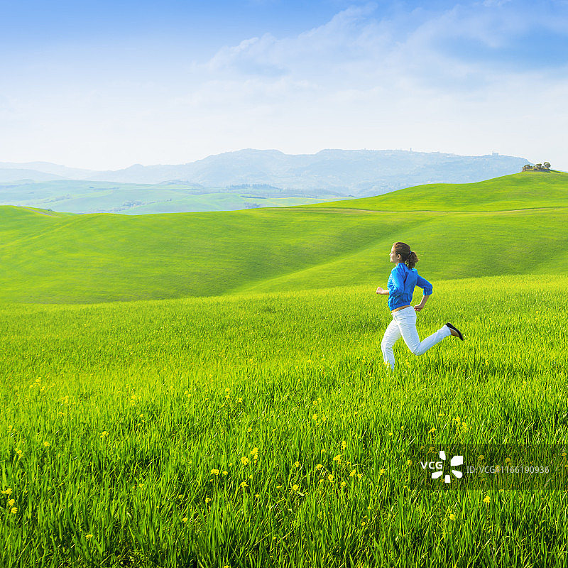 自由:女孩在绿色的田野里奔跑图片素材