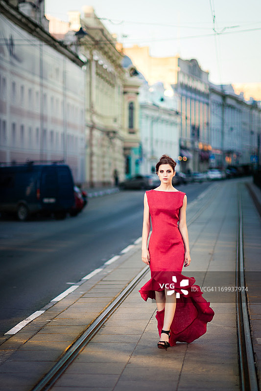 穿着红色衣服的年轻女子在城市街道上图片素材
