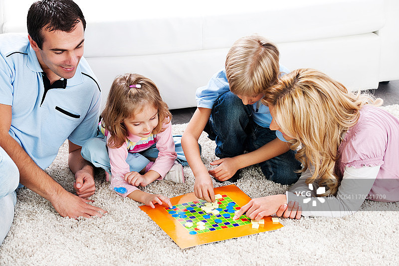 兴高采烈的父母和孩子们玩棋盘游戏。图片素材