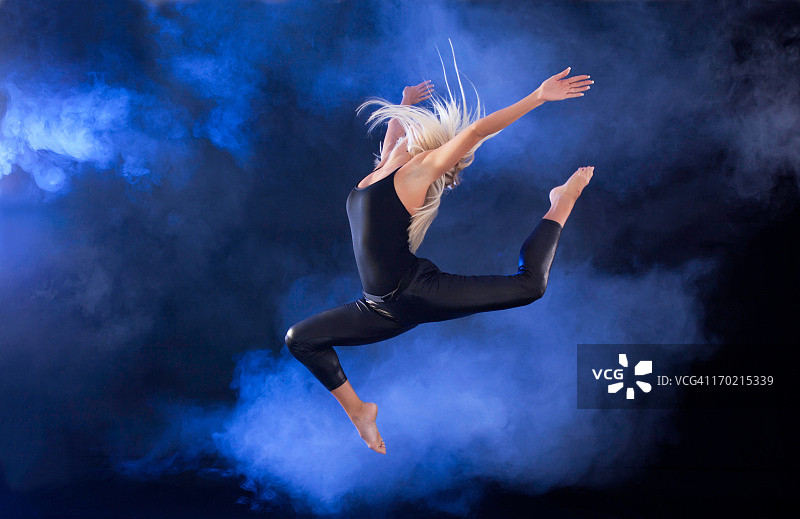 职业芭蕾舞演员在雾中跳跃。图片素材