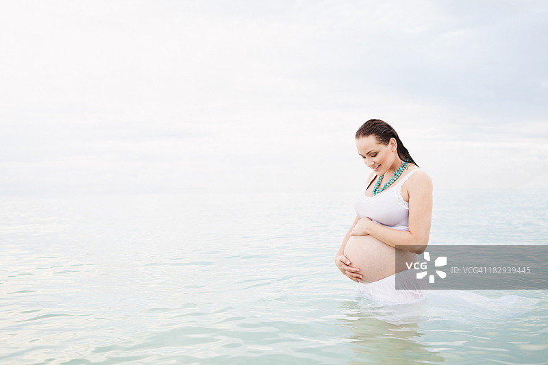 一个白人孕妇站在水里图片素材