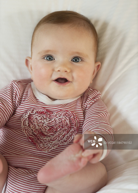 5个月大的女婴躺在白色的毯子上图片素材
