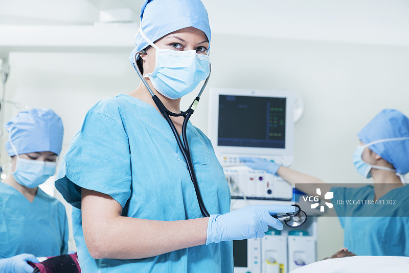 一组外科医生在手术室里，女外科医生拿着听诊器看着摄像机图片素材