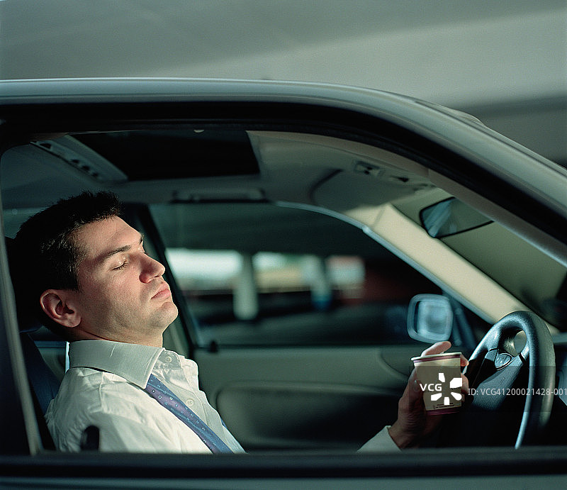 商人在车里休息，拿着咖啡，闭着眼睛，特写图片素材