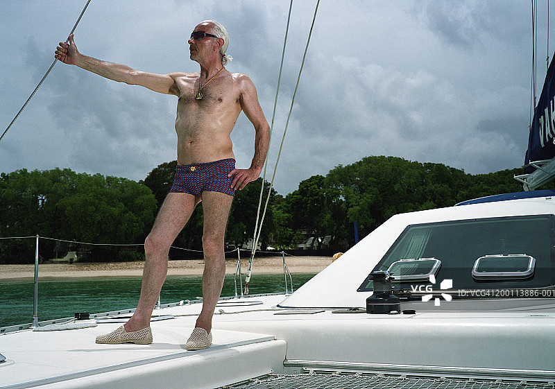 成熟的男人穿着游泳裤，站在船上图片素材