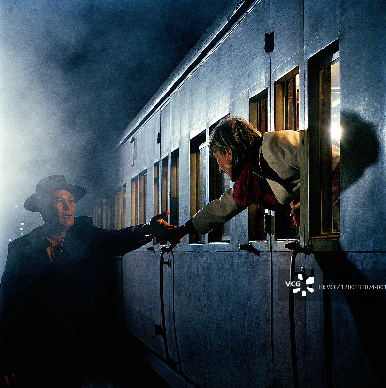 成熟的女人在火车上牵着男人的手，在月台，夜晚图片素材