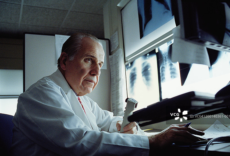 放射科医生看着电脑屏幕，背景是x光片图片素材
