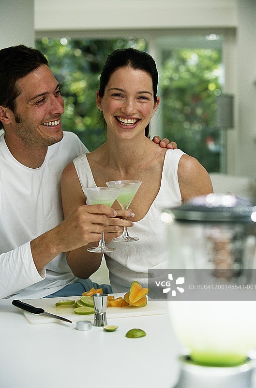 年轻夫妇在厨房喝鸡尾酒，肖像图片素材