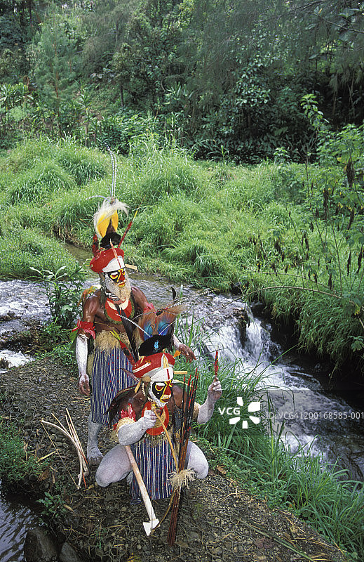 两个穿着部落服装的人在瀑布附近，高视阔步图片素材