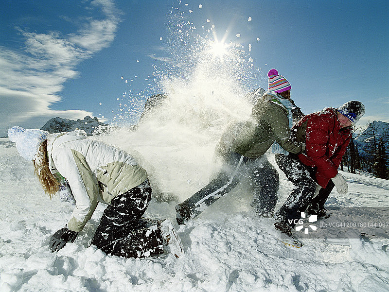 3个青少年(15-17岁)在雪地里打闹，侧视图图片素材